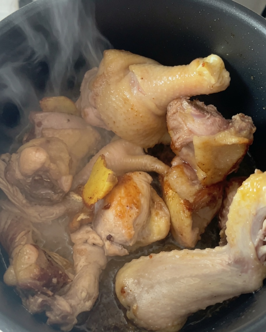Vapore che sale dai pezzi di pollo nella pentola a pressione dopo aver aggiunto acqua calda.