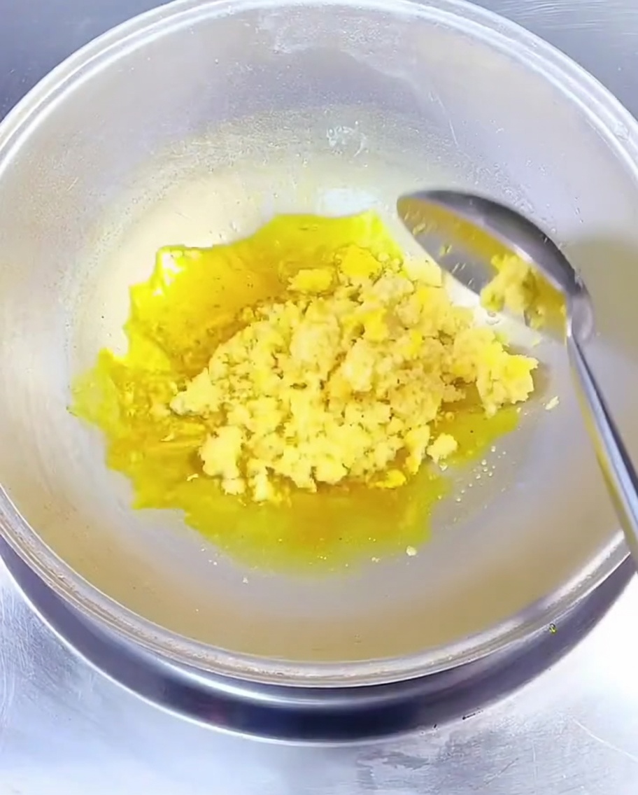 Aglio tritato mescolato nellolio di colza caldo in un wok con un cucchiaio di metallo.