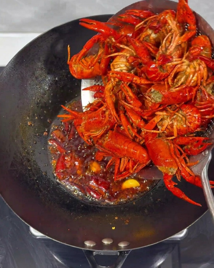 Gamberi fritti uniti alla salsa piccante in un wok.
