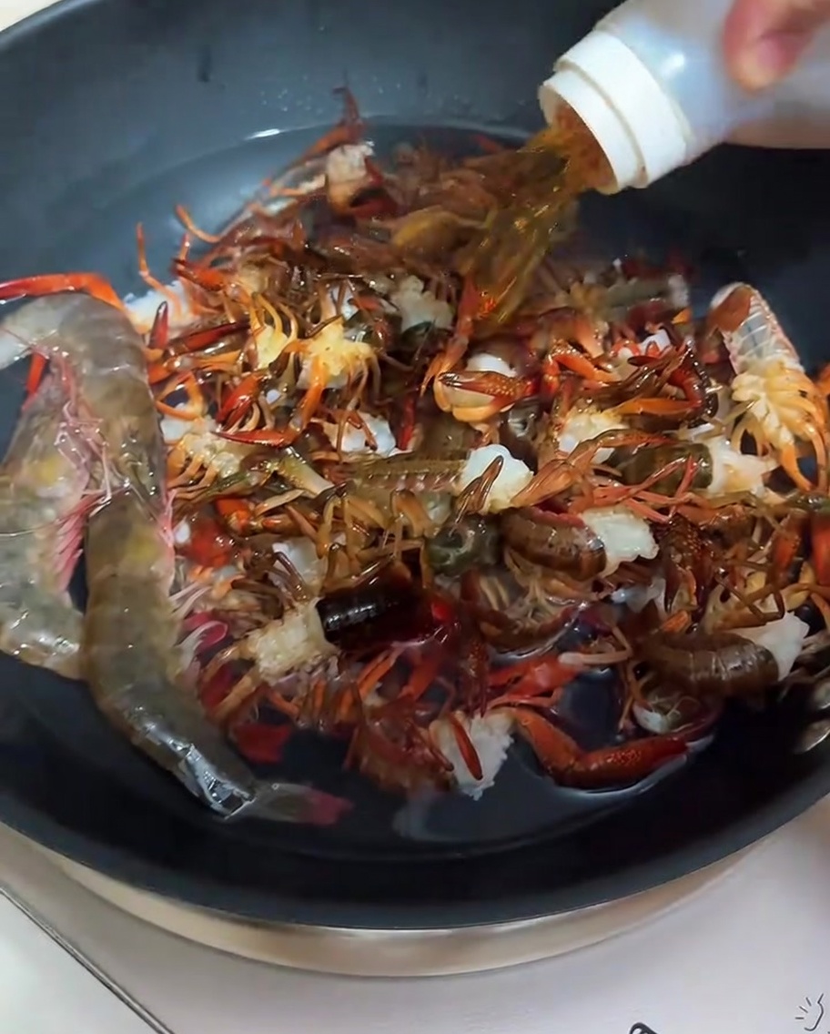 Gamberi che vengono sbollentati in una padella con acqua e vino da cucina.