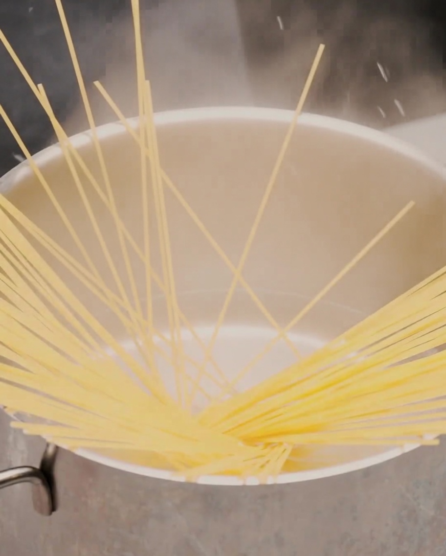 Un cucchiaio di crema di aglio arrosto aggiunto in una padella nera.