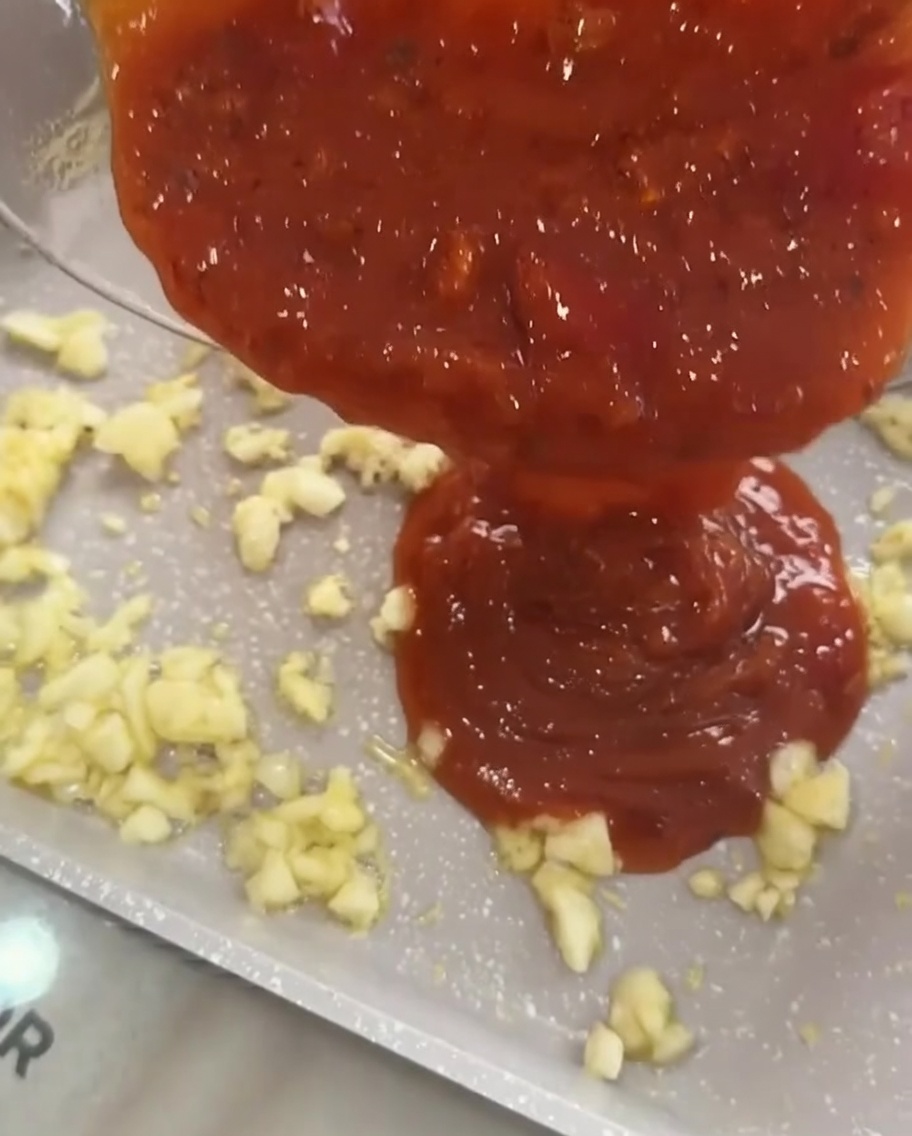 Ragù di carne versato sopra laglio soffritto in padella.