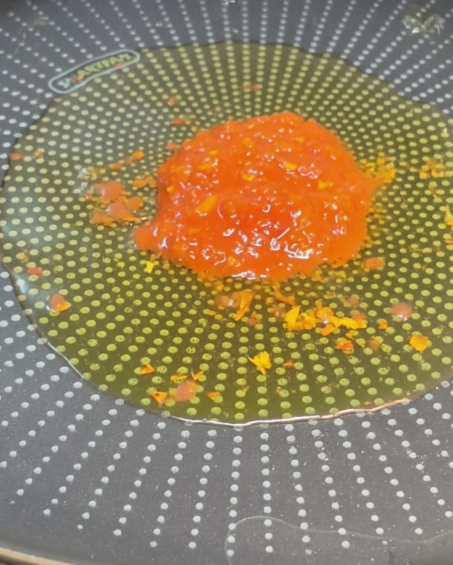 Un mucchio di pomodori a cubetti rossi brillanti al centro di una padella con olio condito.