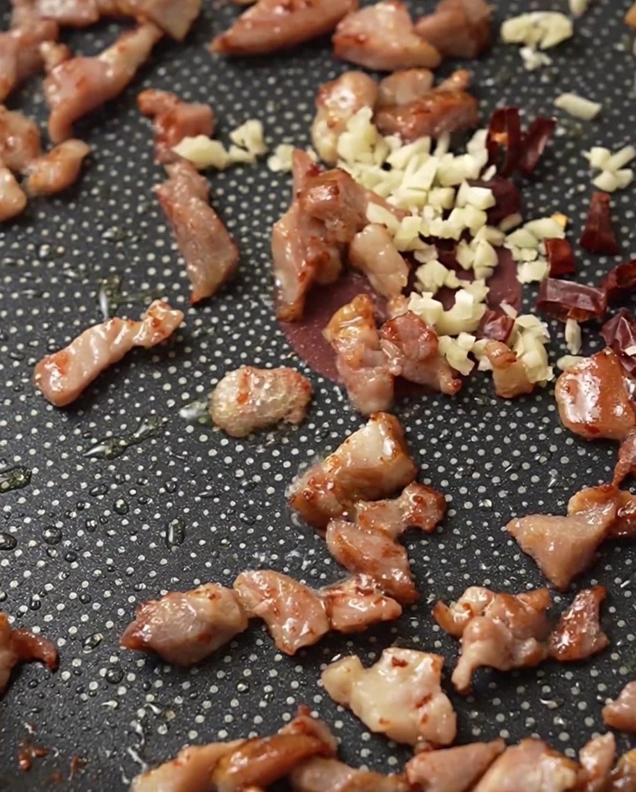Pancetta, aglio tritato e peperoncino secco che sfrigolano in padella.