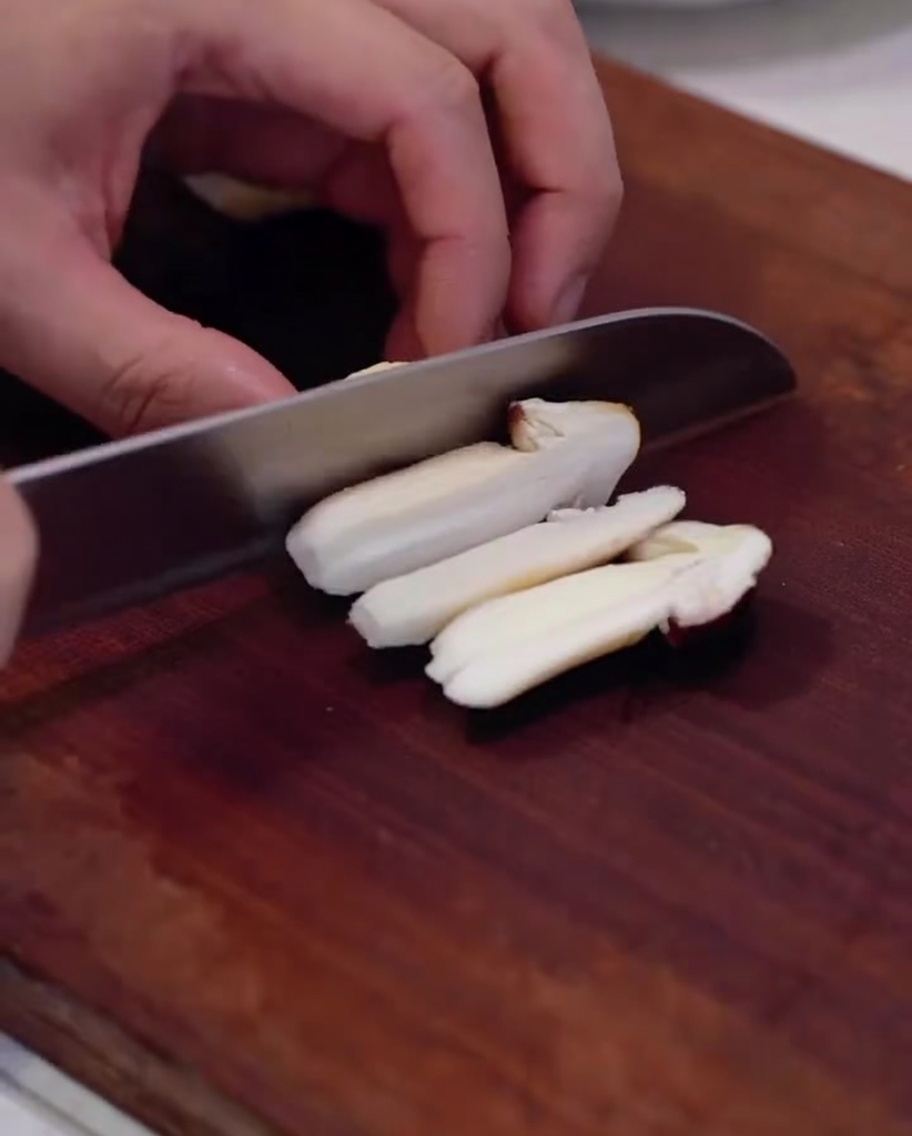 Funghi pioppini freschi affettati su un tagliere di legno.
