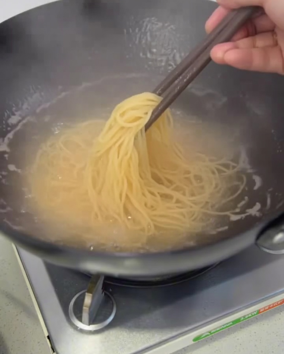Spaghetti cotti sollevati dalla pentola per scolarli.