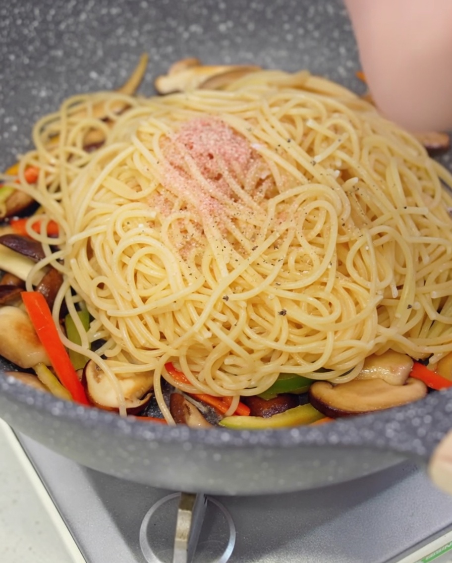 Pepe nero macinato fresco sugli spaghetti in padella.