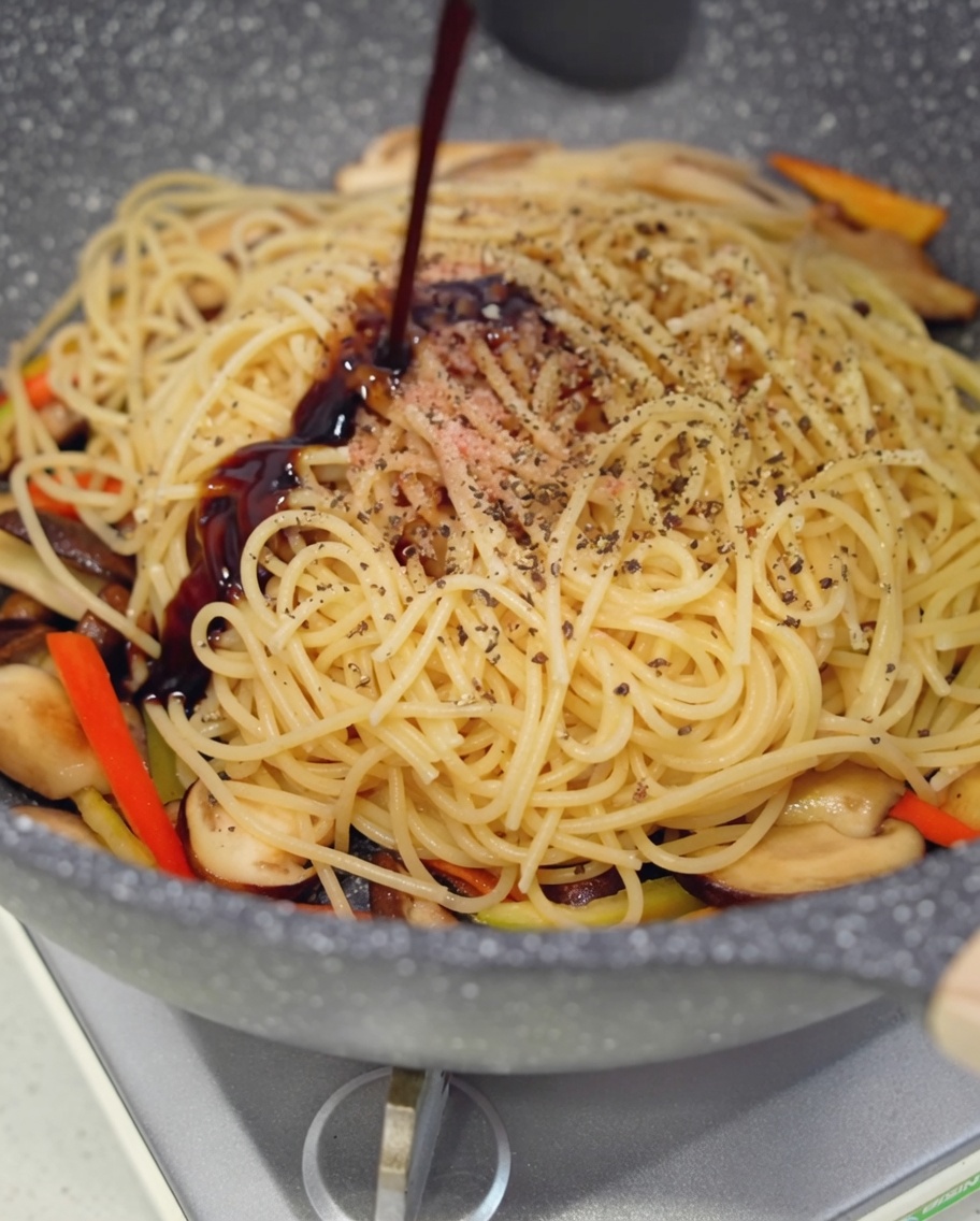 Salsa di ostriche vegana versata sugli spaghetti in padella.