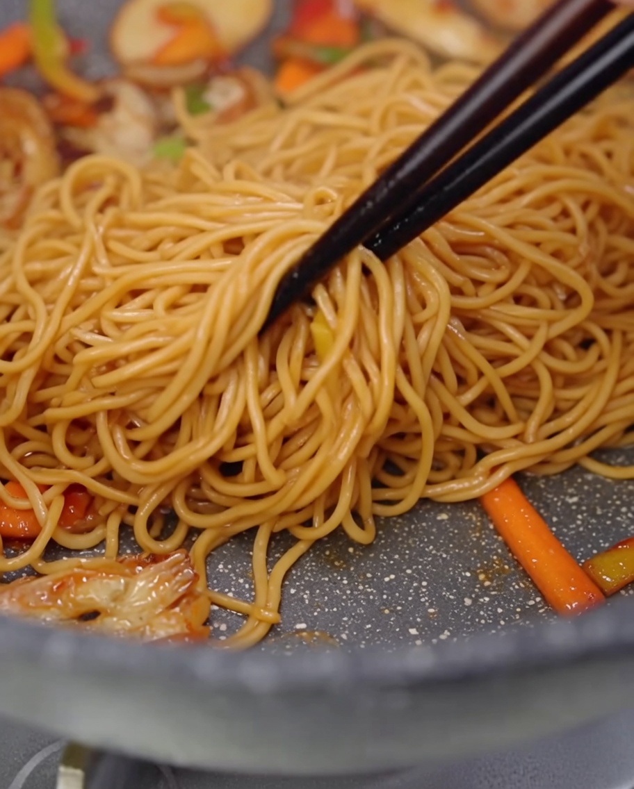 Dettaglio di spaghetti, funghi e peperoni saltati in padella.