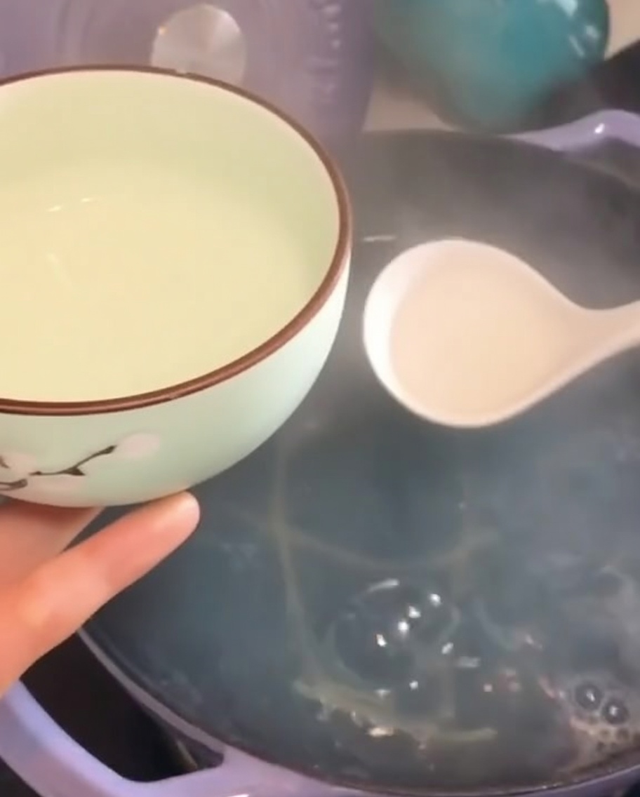 Una piccola ciotola riempita di acqua di cottura della pasta con un mestolo.