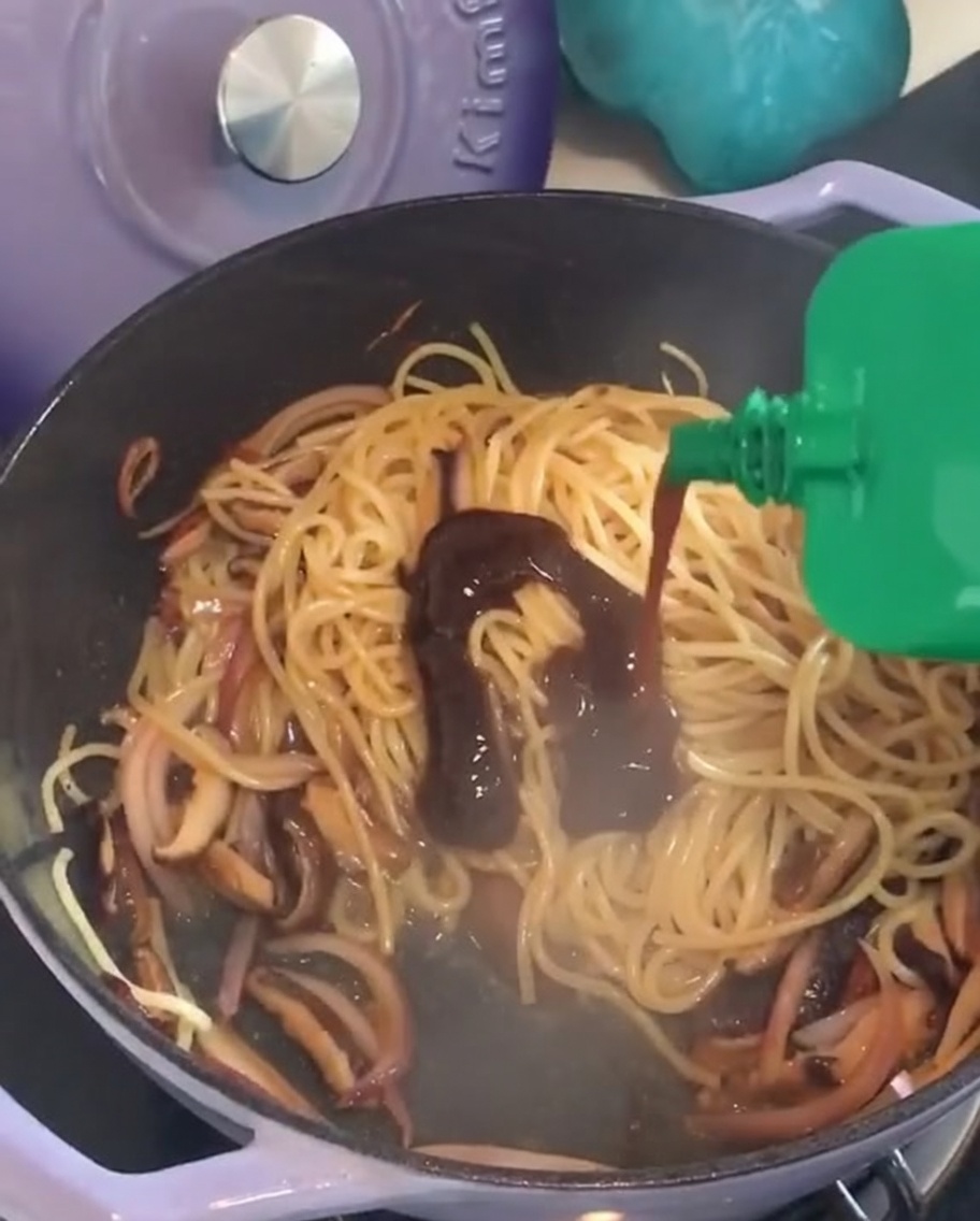 Aggiunta della salsa al pepe nero sulla pasta in padella.
