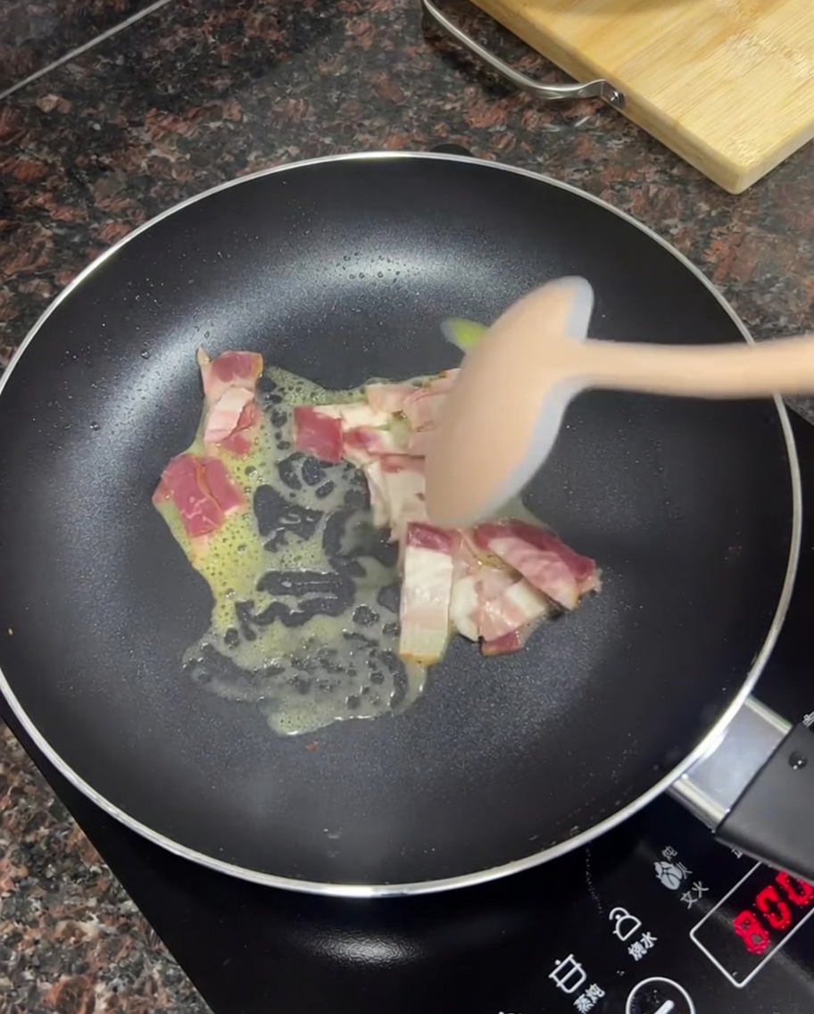 Pezzetti di bacon che friggono nel burro fuso in una padella.