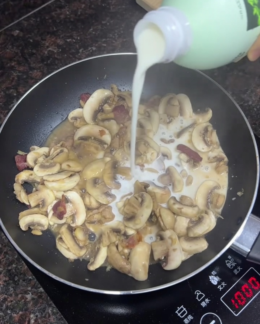 Latte versato in una padella con funghi e bacon saltati.