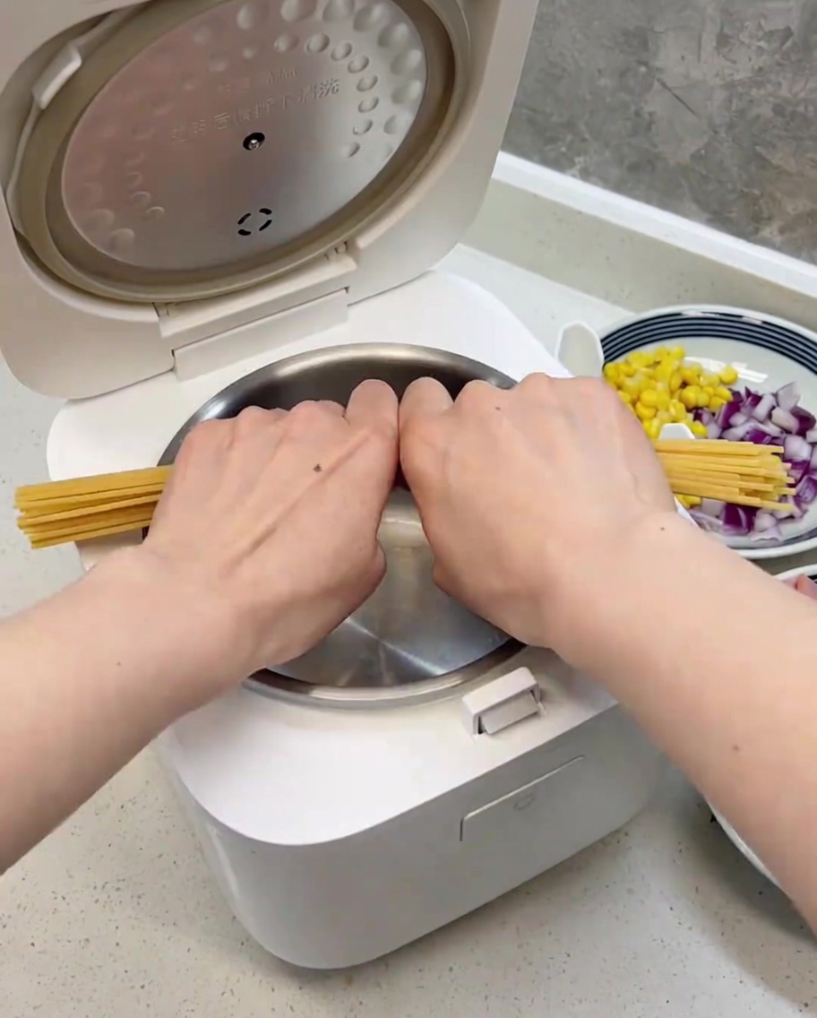 Spaghetti spezzati a metà, disposti ordinatamente allinterno della ciotola pulita della cuociriso.