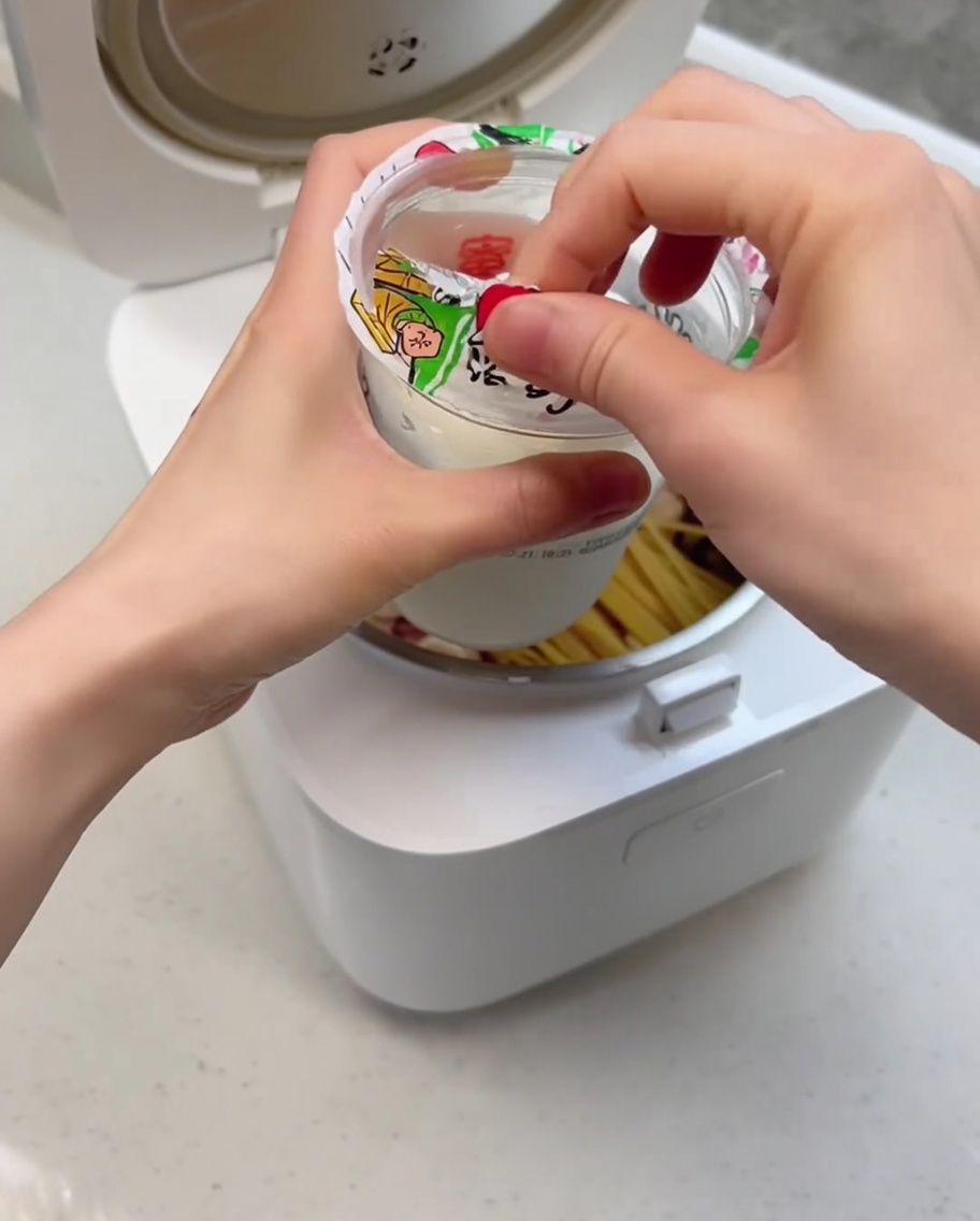 Un primo piano del gelato cremoso che viene versato nella pentola della cuociriso sopra gli ingredienti.