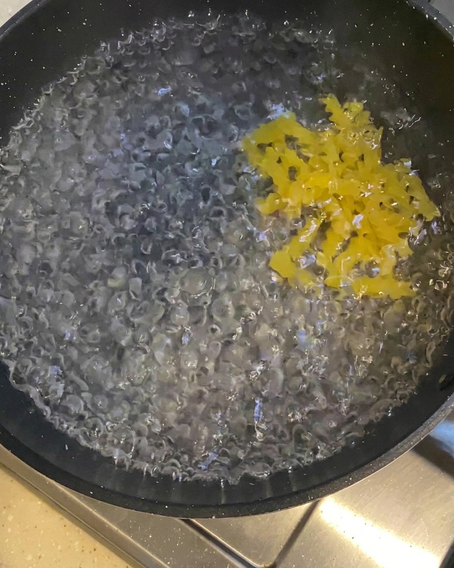 Pasta rotini che viene immersa in una pentola con acqua bollente.