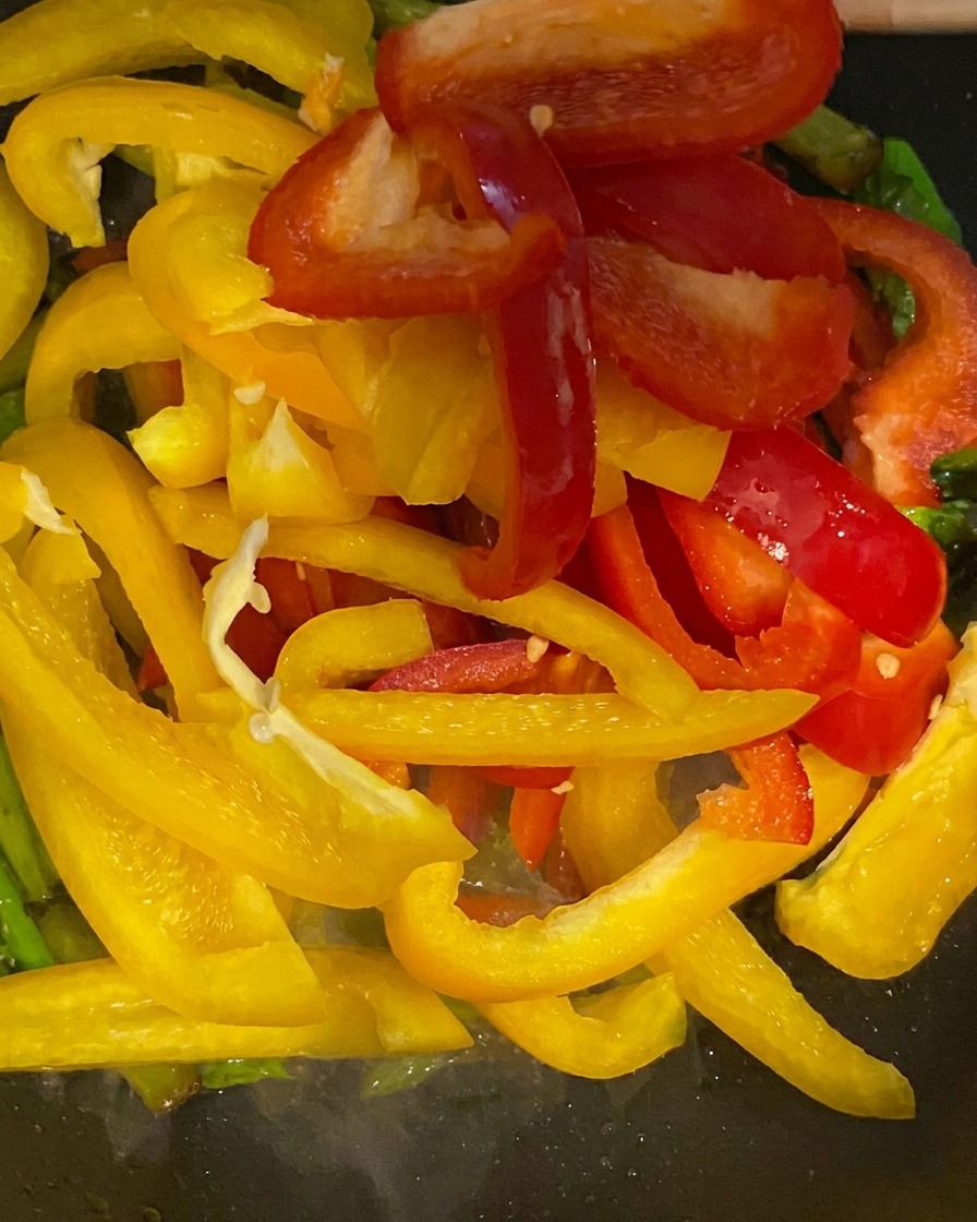 Listarelle di peperoni rossi e gialli aggiunte in padella con gli asparagi.