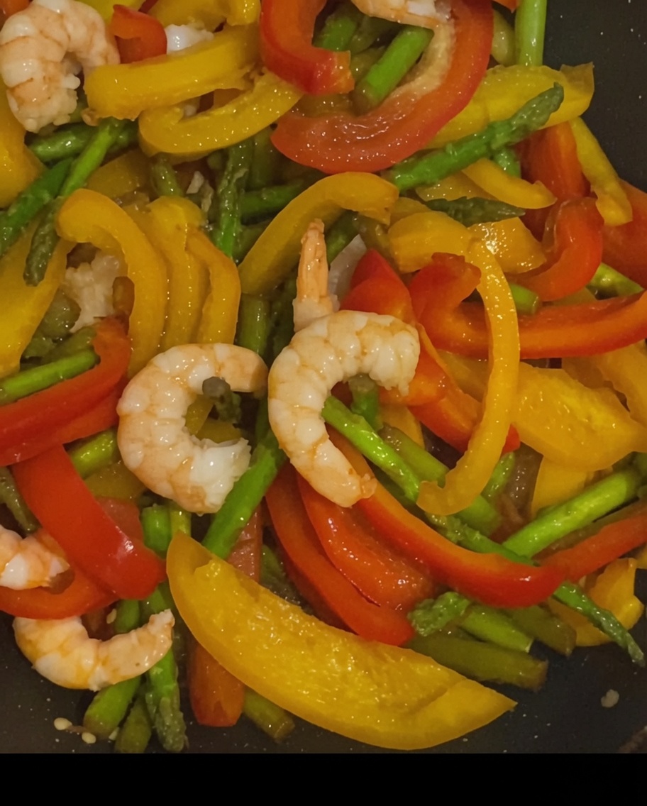 Pasta con gamberi e verdure in padella spolverata con pepe nero.
