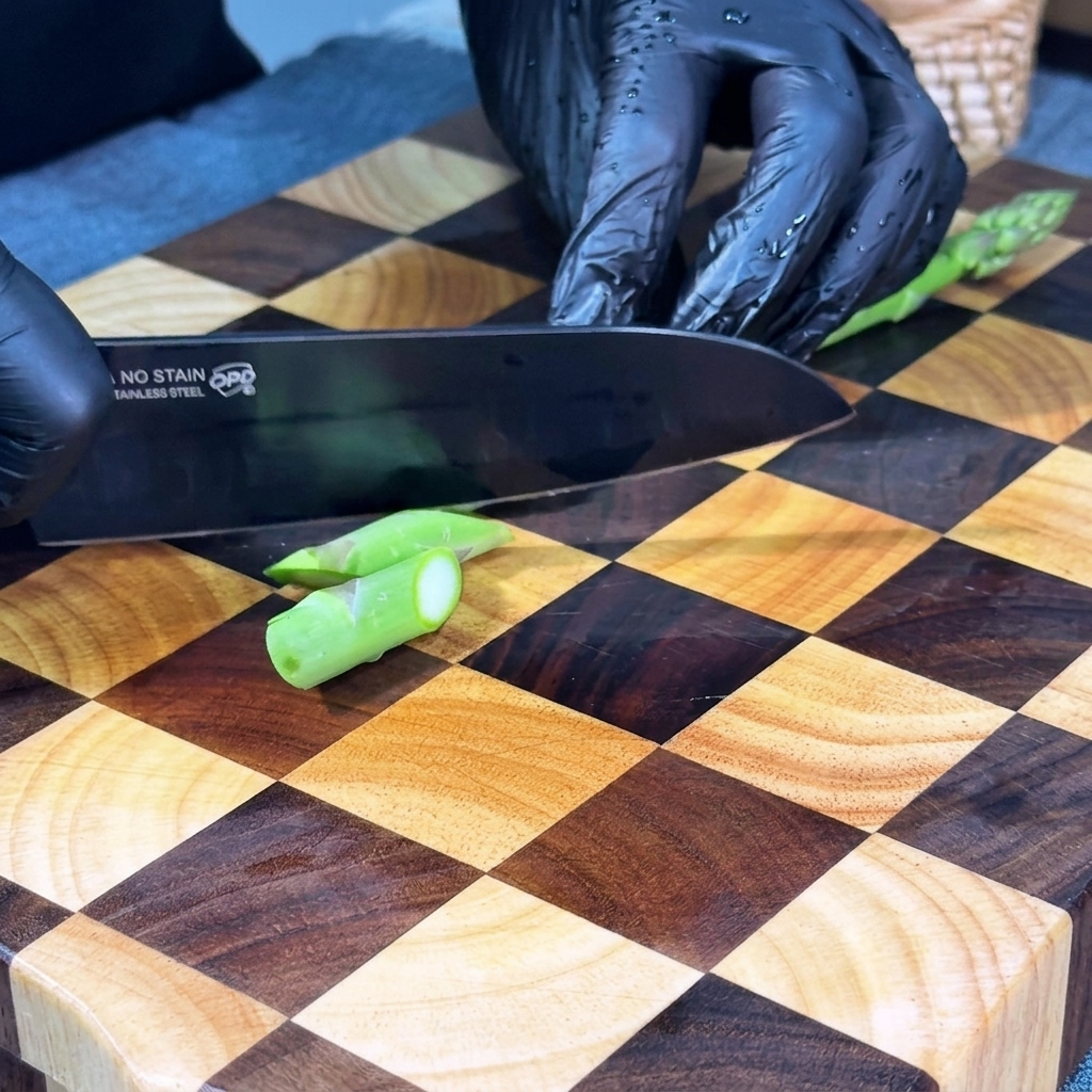Asparagi freschi tagliati a piccoli pezzi diagonali su un tagliere.