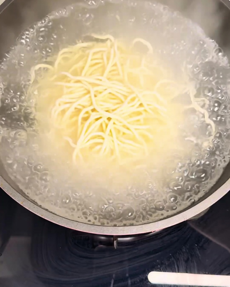 Noodles freschi immersi in una pentola di acqua bollente.