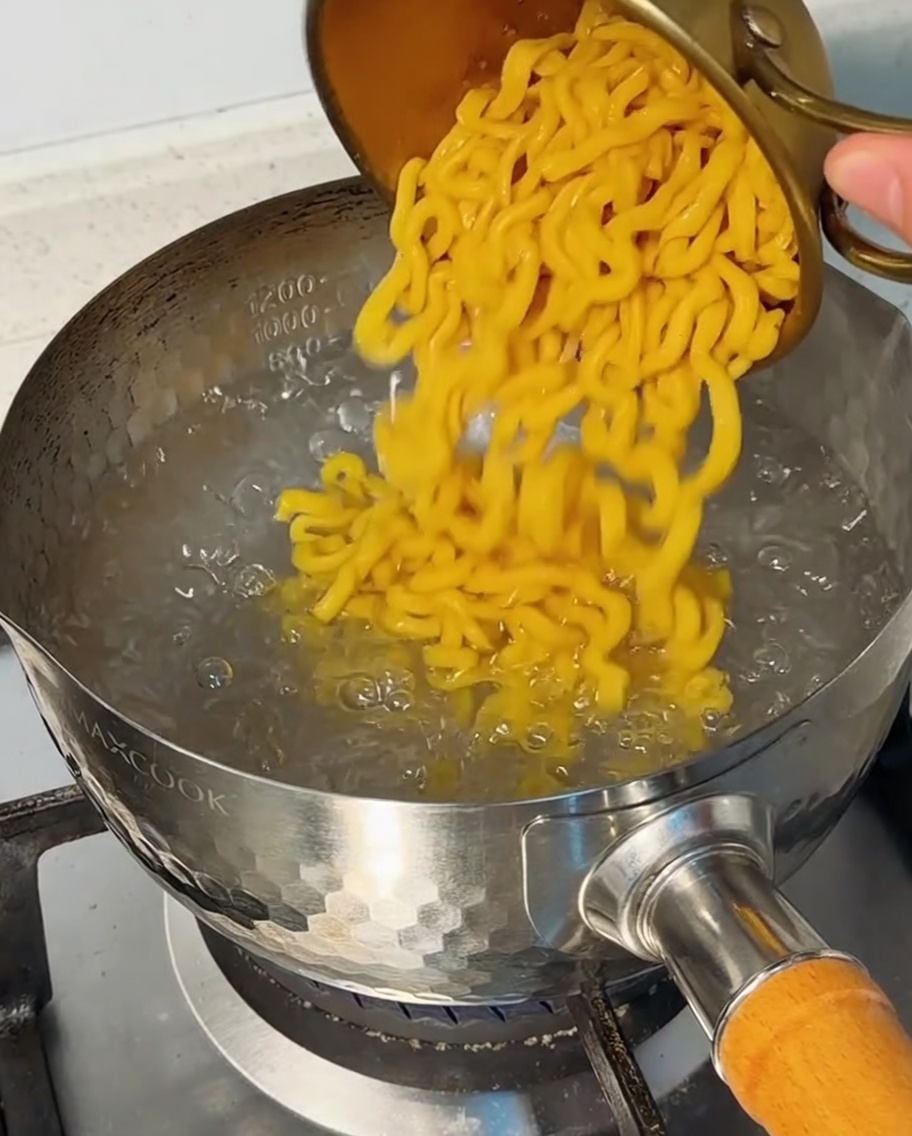Pasta corta versata in una pentola di acqua bollente.