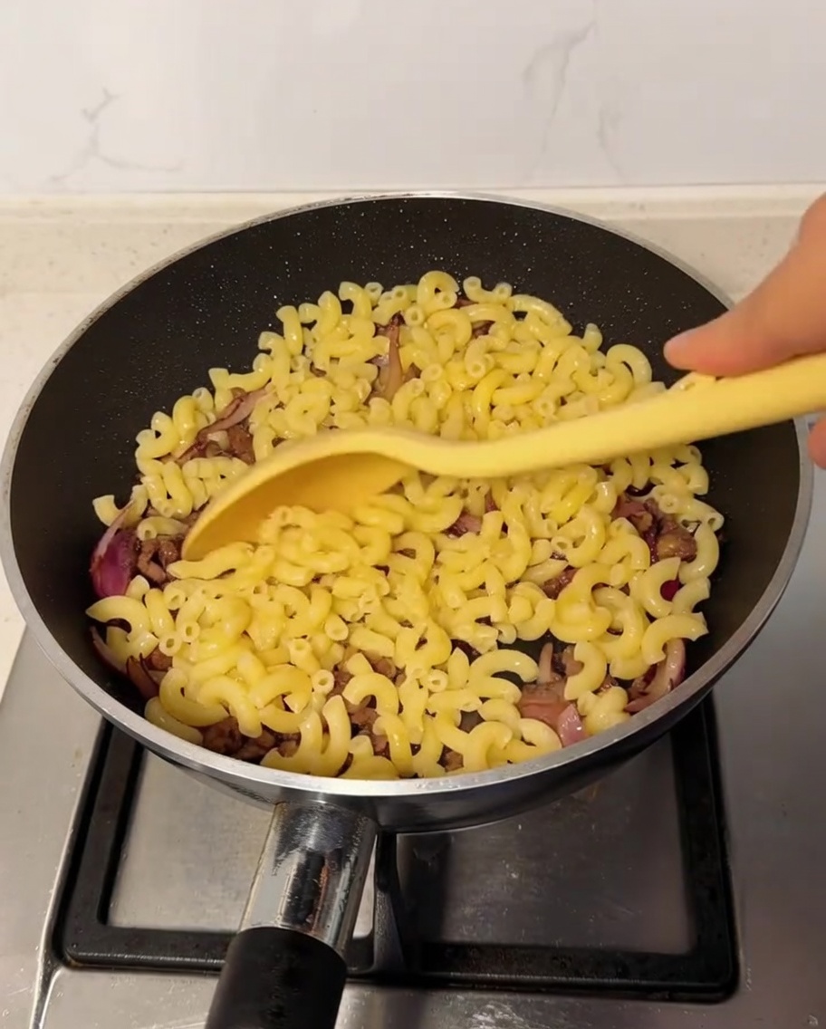 Maccheroni cotti aggiunti nella padella con il mix di manzo e cipolla.