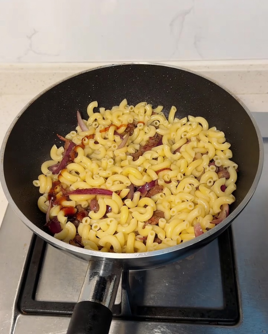 Salsa di ostriche e salsa di soia versate sopra i maccheroni in padella.