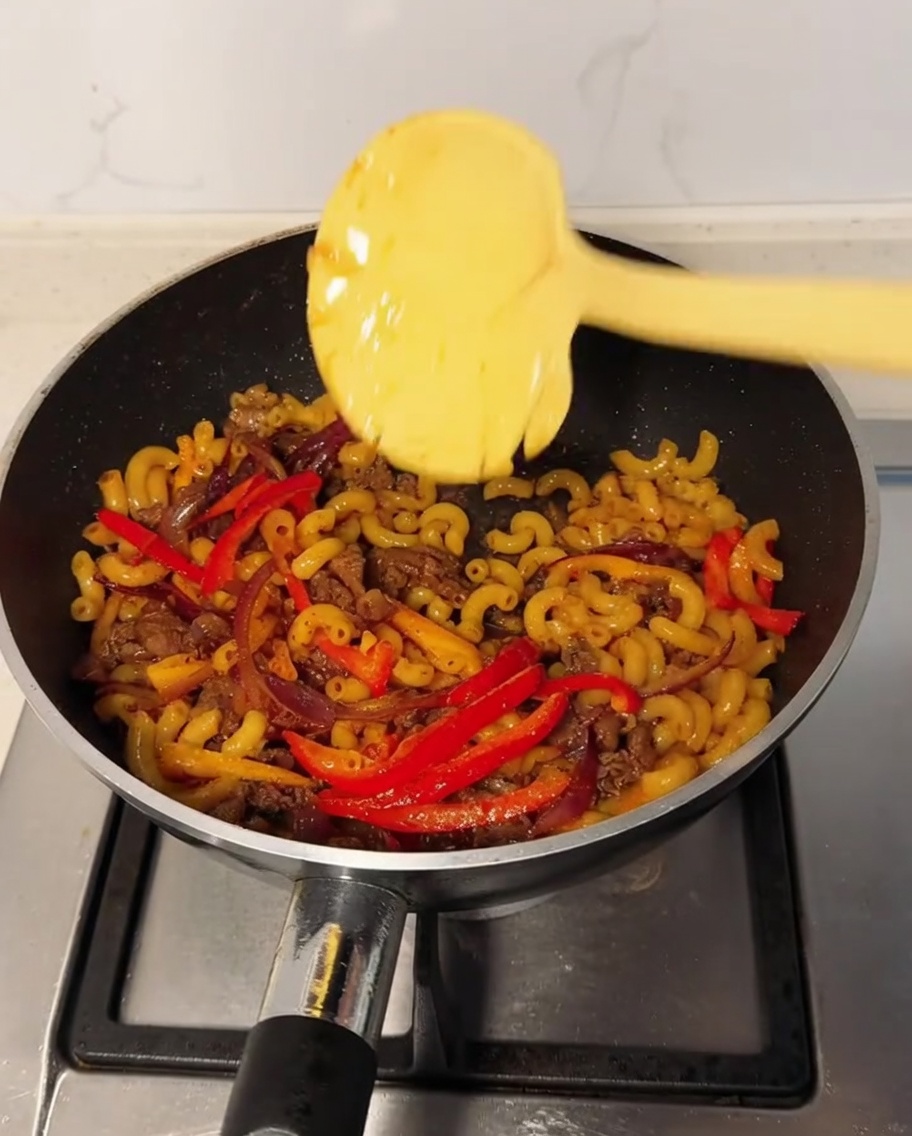 Una fetta di formaggio sopra i maccheroni in padella con pepe nero spolverato.