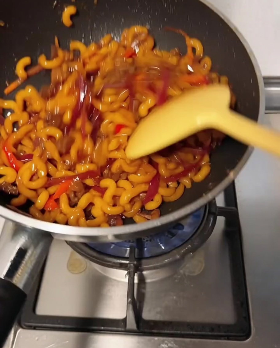 Il composto di maccheroni mescolato nella padella mentre il formaggio si scioglie.