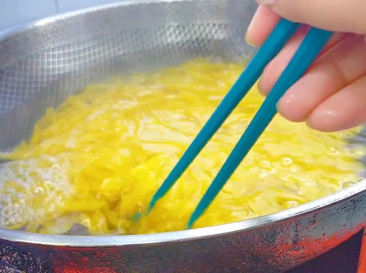 Bacchette blu che mescolano penne bollenti in un wok dacciaio inossidabile.