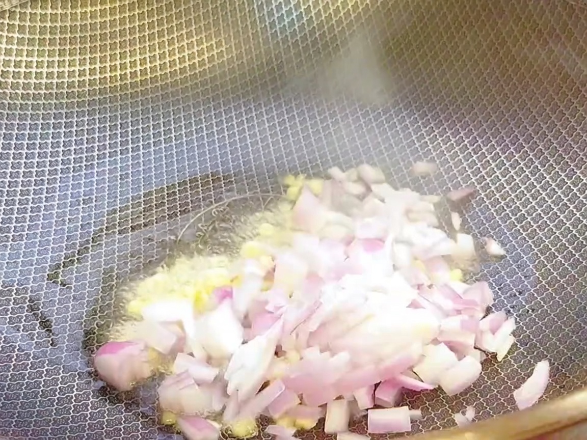 Aglio tritato e cipolla tritata saltati in un wok caldo con olio.