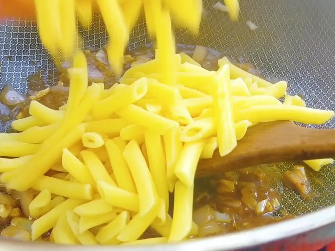 Penne cotte aggiunte al wok con la base di salsa al pepe nero.