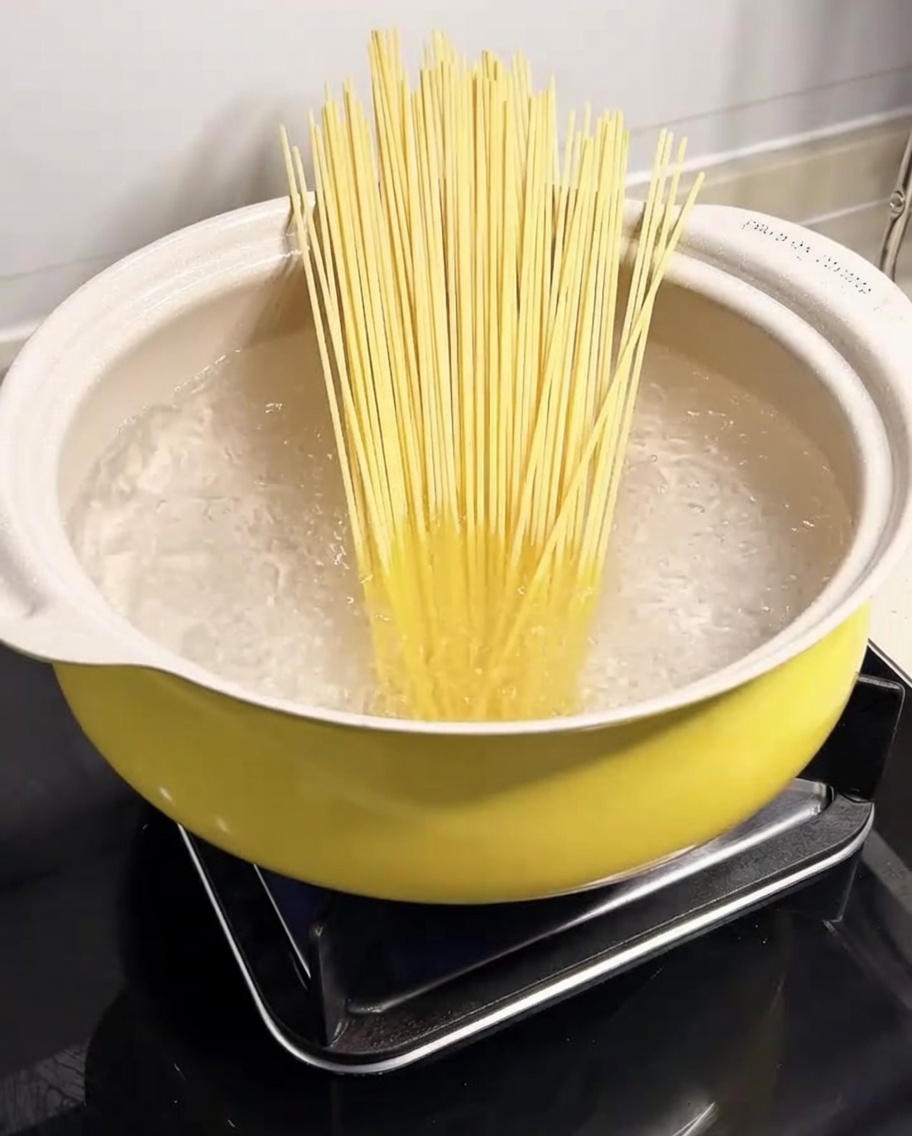 Spaghetti immersi in una pentola di acqua bollente.