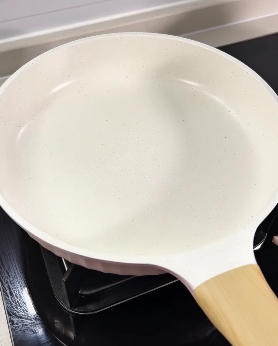 Cubetti di guanciale che rosolano in una padella bianca nel loro stesso grasso.