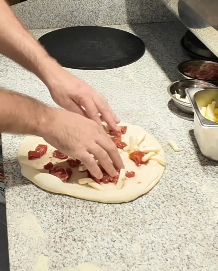 Mozzarella a pezzetti aggiunta alla base della pizza.