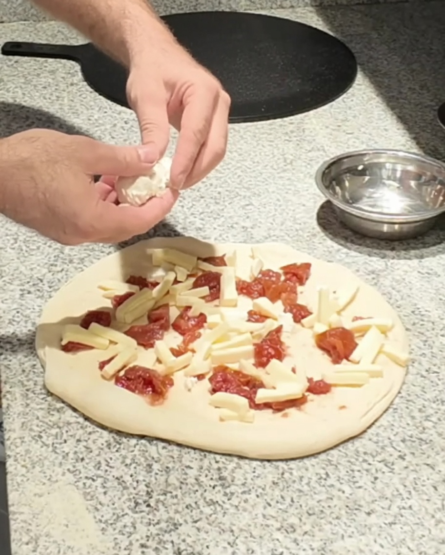 Formaggio di capra fresco posizionato sulla pizza.