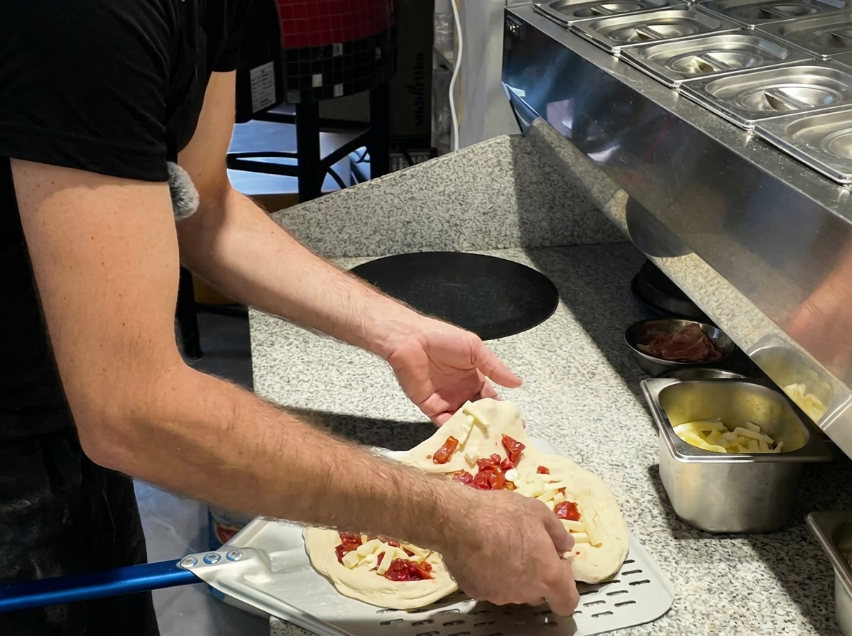 Pizza infornata con una pala di metallo.
