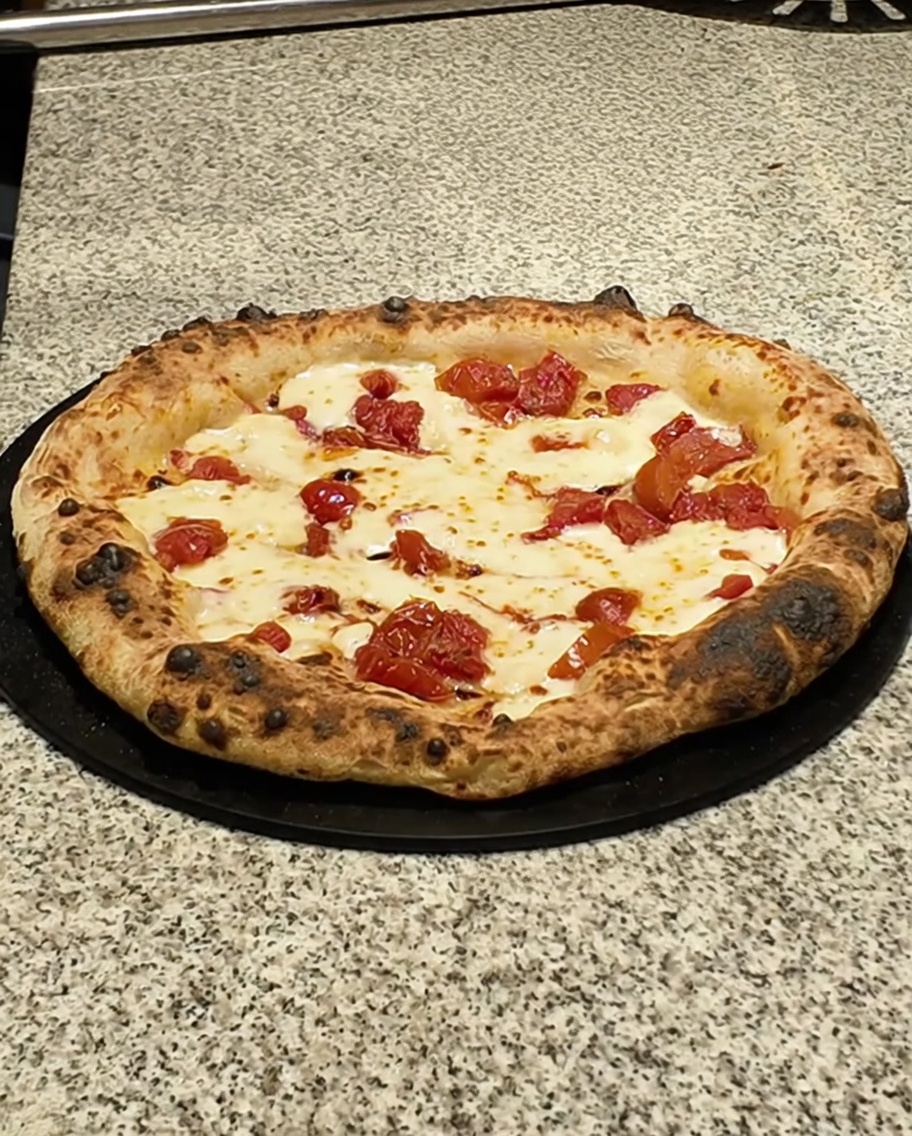 Pizza appena sfornata arricchita con fette di pancetta.