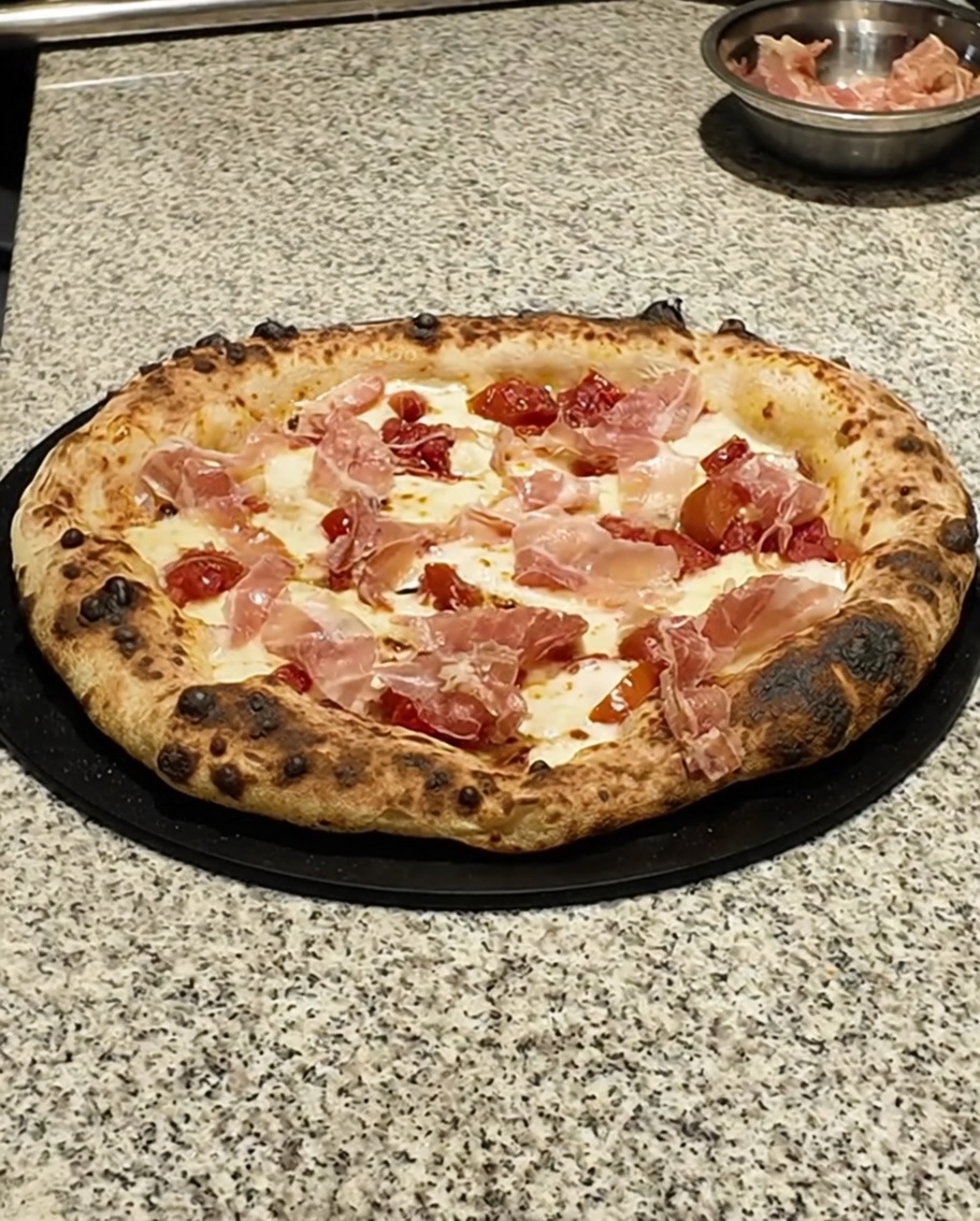 Primo piano di foglioline di timo fresco distribuite su una pizza appena sfornata.