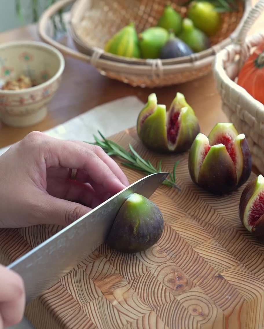 Fichi freschi con un taglio a croce su un tagliere di legno, pronti per essere farciti.