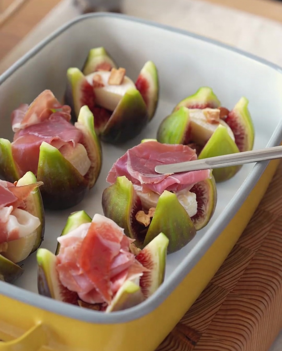 Fichi ripieni guarniti con fettine di prosciutto e rametti freschi di rosmarino.