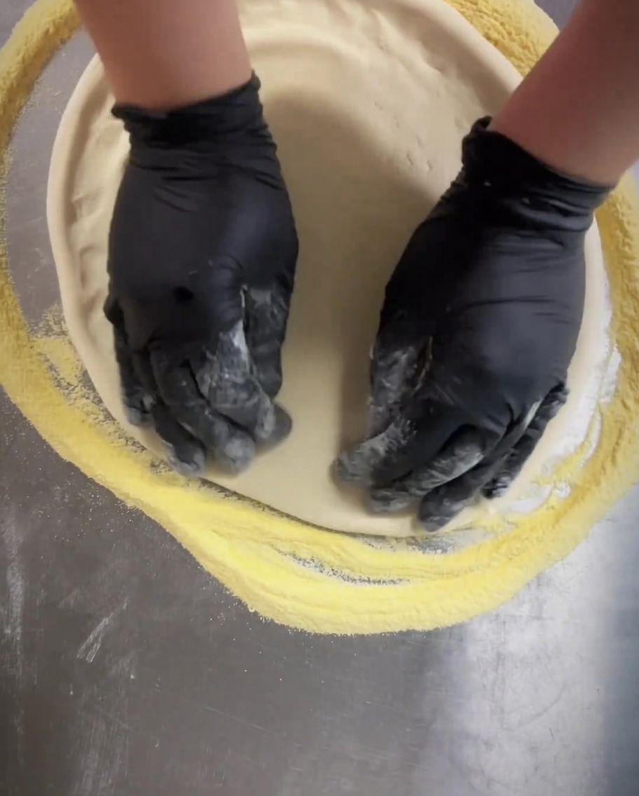 Un attrezzo buca-impasto fatto rotolare sulla base della pizza per creare piccoli fori uniformi.