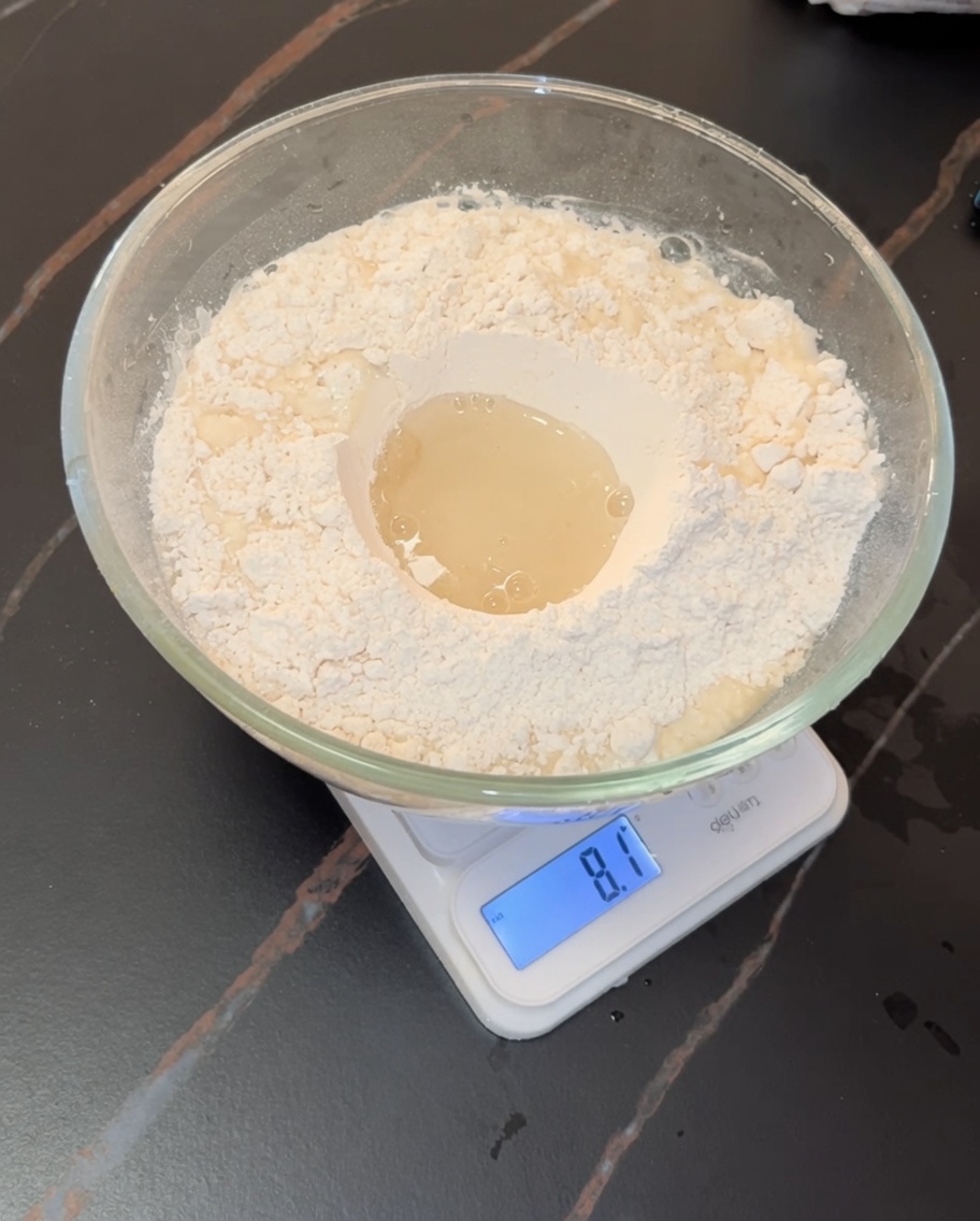 Mani che lavorano un impasto morbido per pizza allinterno di una ciotola di vetro.