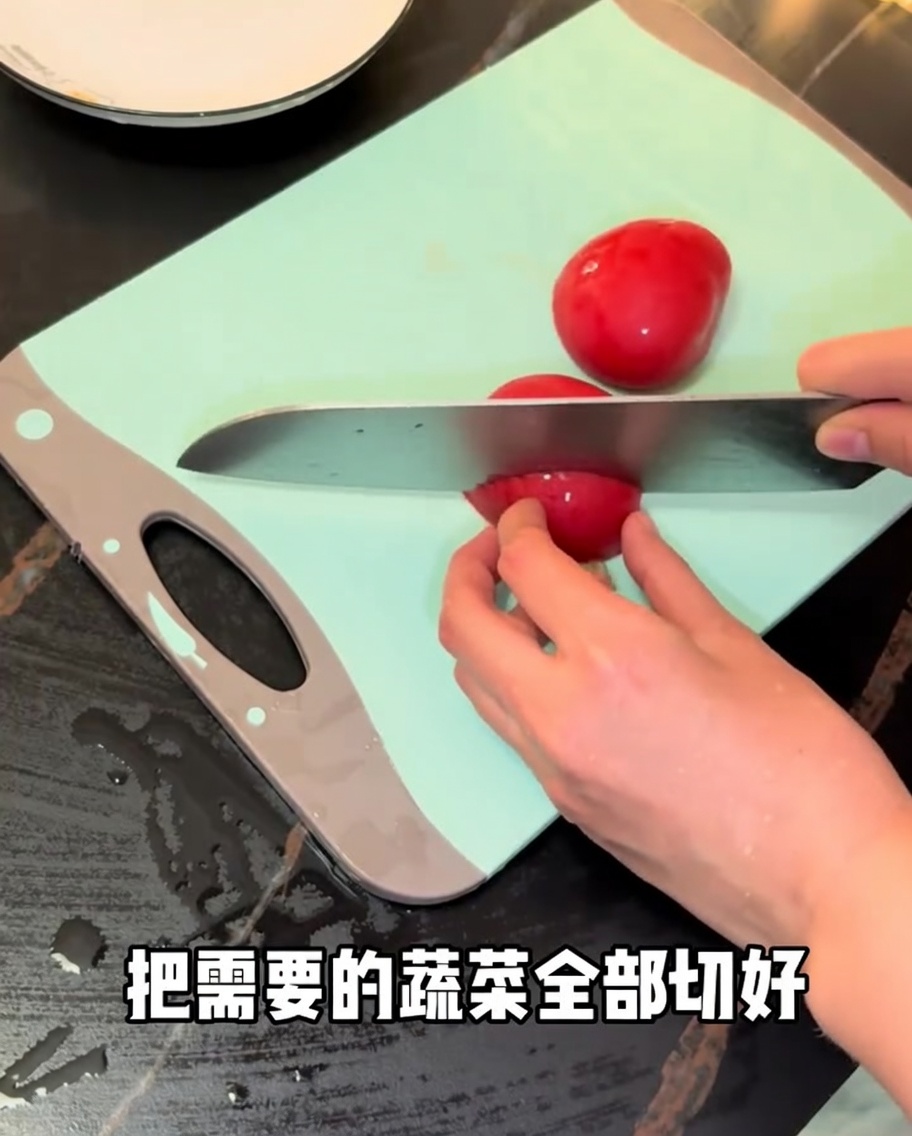 Pomodori rossi freschi tagliati con un coltello da chef su un tagliere verde.