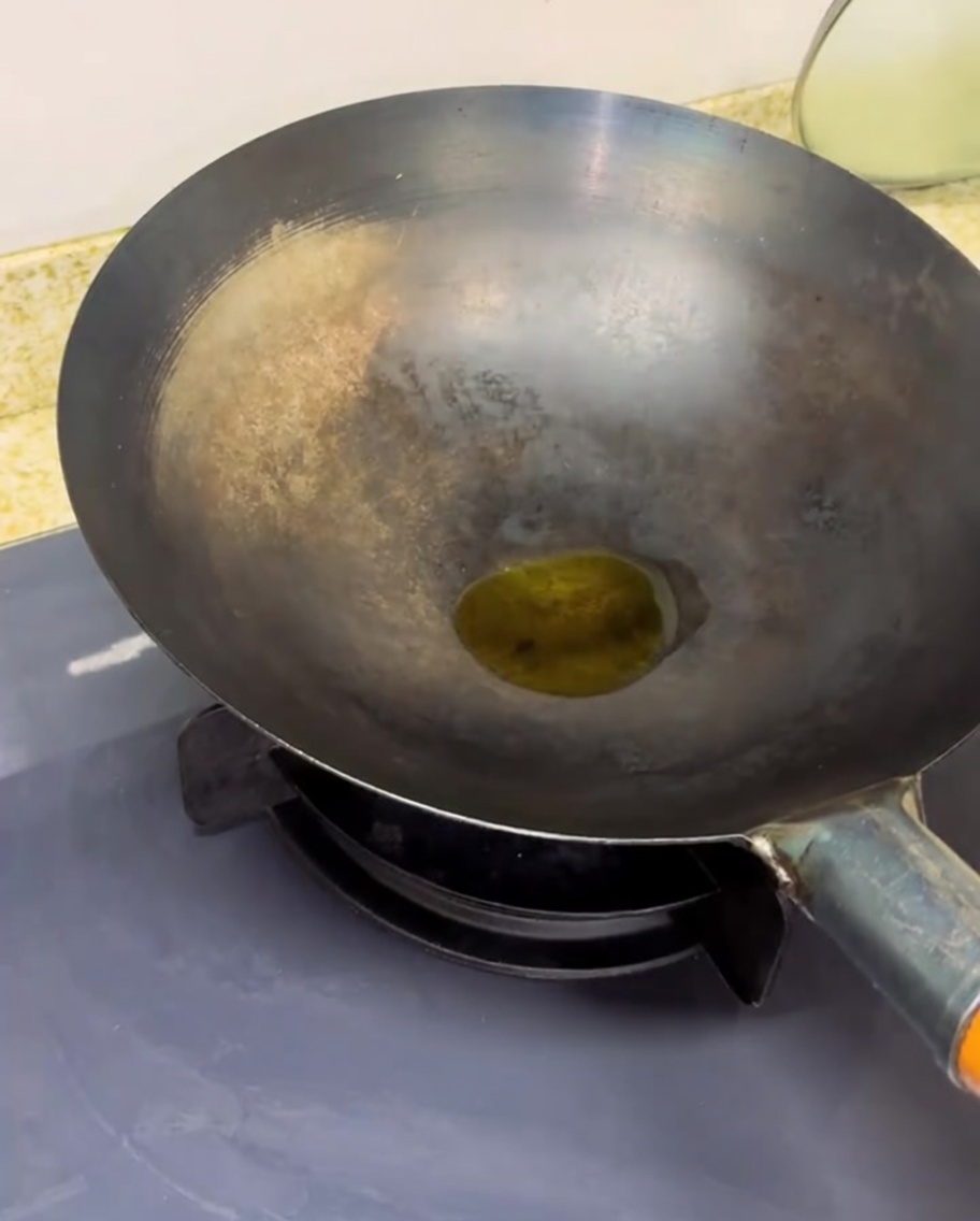 Pomodori a cubetti che cuociono in un wok ben caldo, con vapore e liquidi in riduzione.