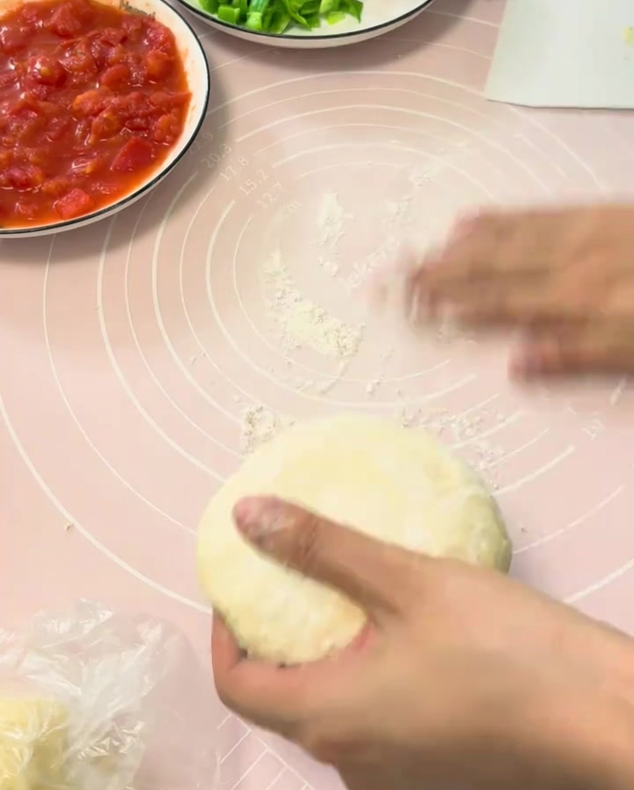 Un panetto di impasto per pizza lievitato steso su un tappetino in silicone rosa.
