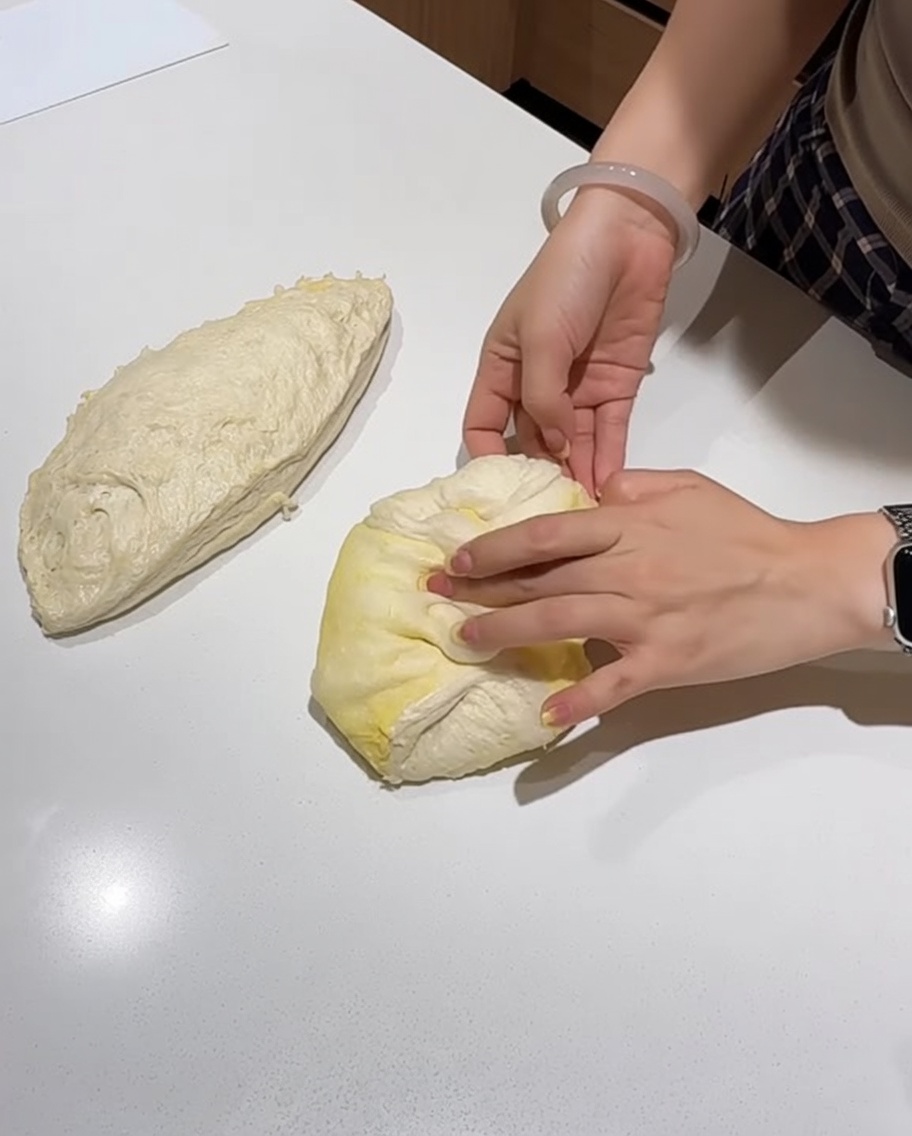 Le mani modellano un panetto di pizza in un disco teso.
