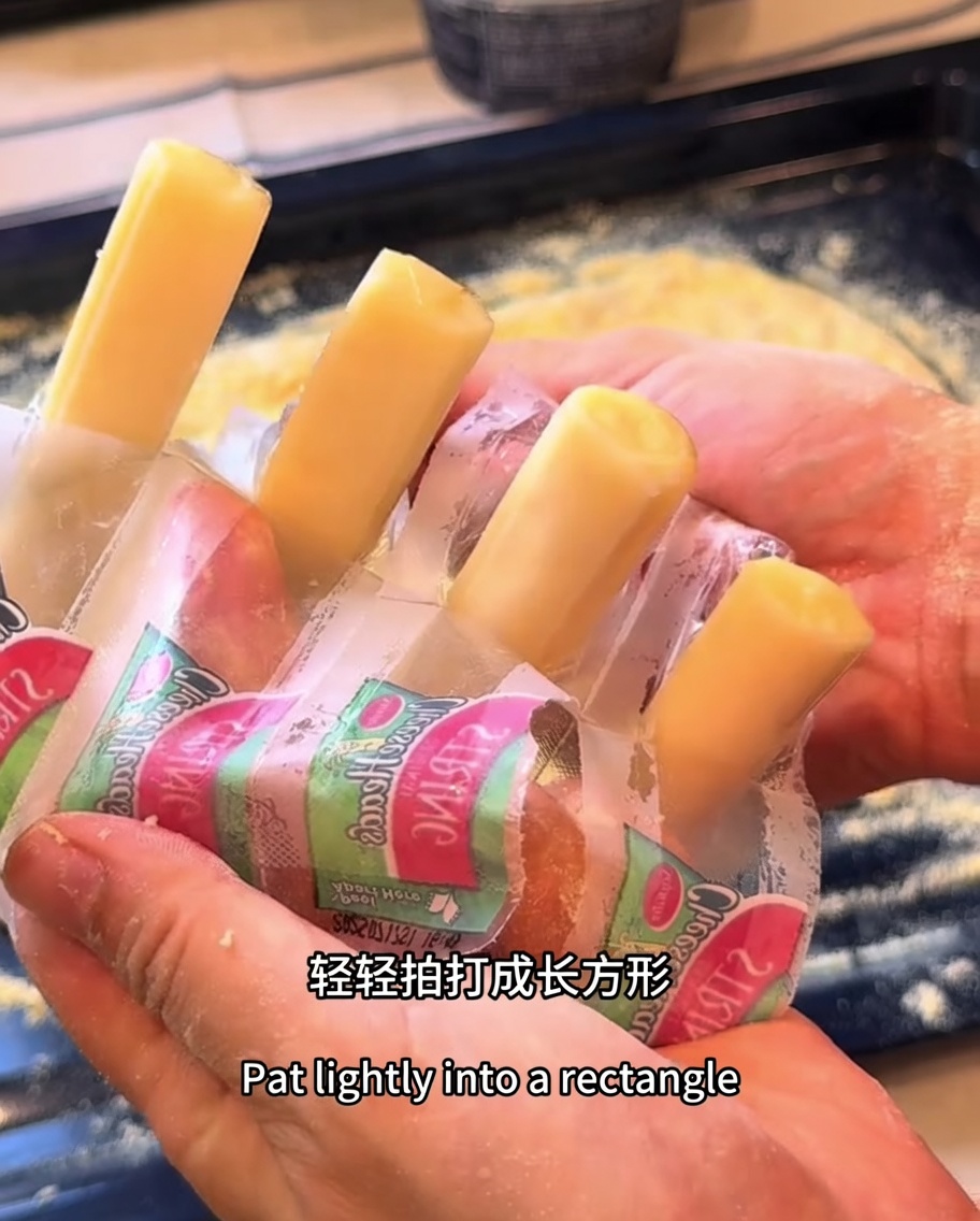 Bastoncini di mozzarella posizionati lungo il perimetro dellimpasto rettangolare della pizza.
