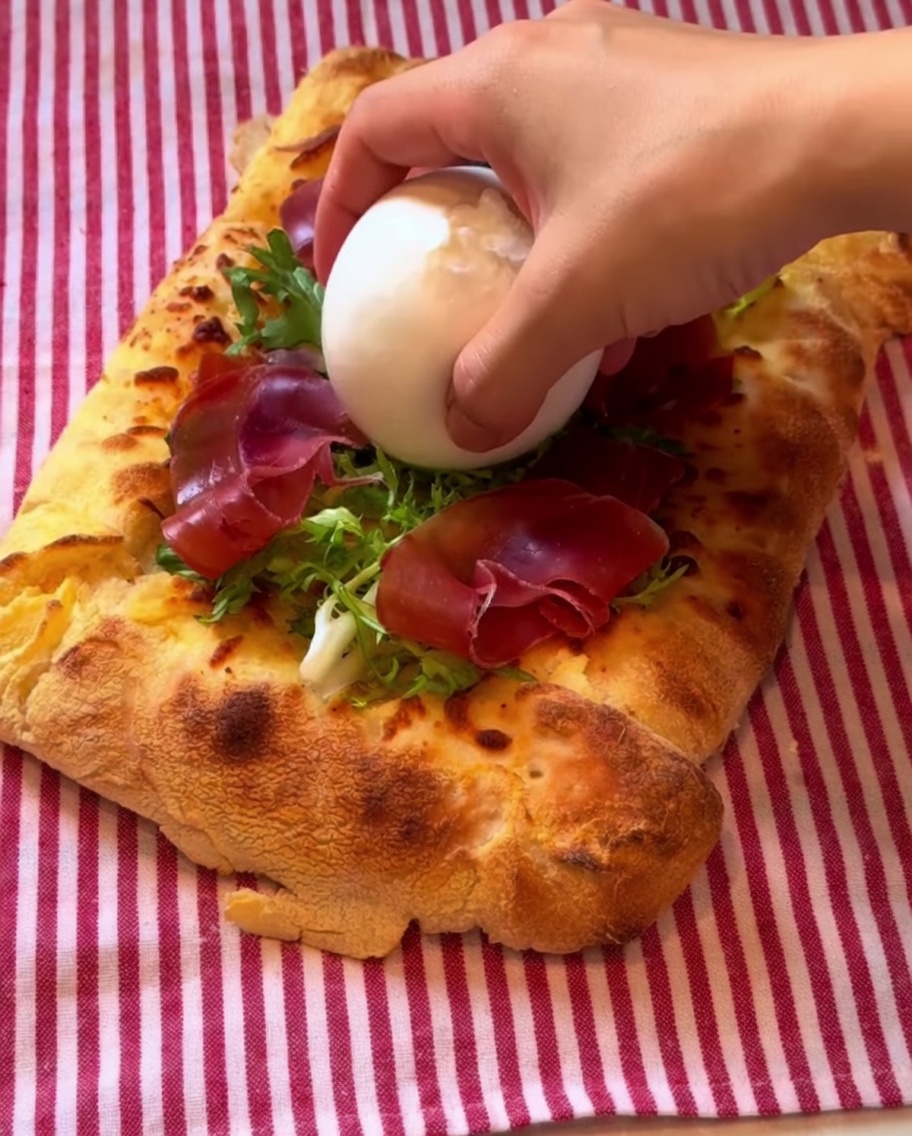 Una palla di burrata posizionata sulla pizza e condita con vinaigrette balsamica.