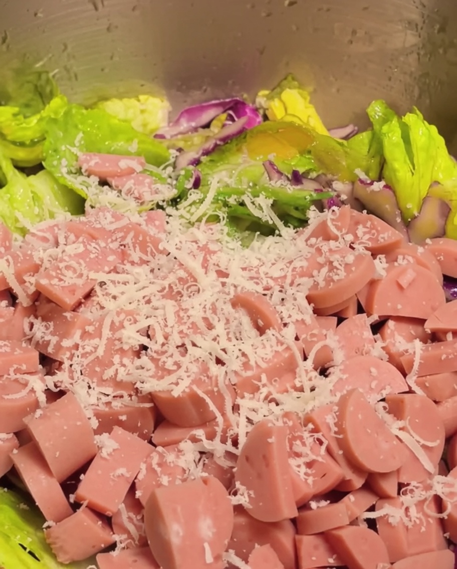 Prosciutto a cubetti e parmigiano grattugiato aggiunti al mix di insalata.